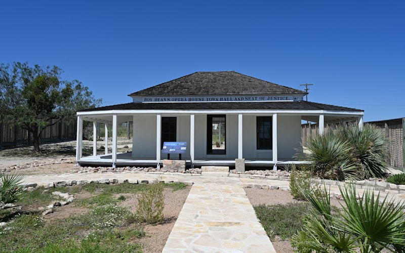 White house with wrap-around porch under blue sky